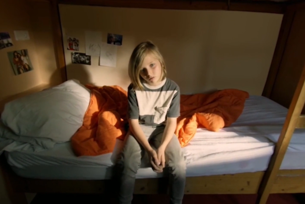 Child sitting on a bed looking sad. This screenshot is from one of the fostering and adoption virtual reality films created by Cornerstone VR.